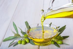Bottle pouring virgin extra olive oil in a glass bowl