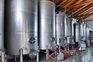 Stainless steel wine vats in a row inside the winery